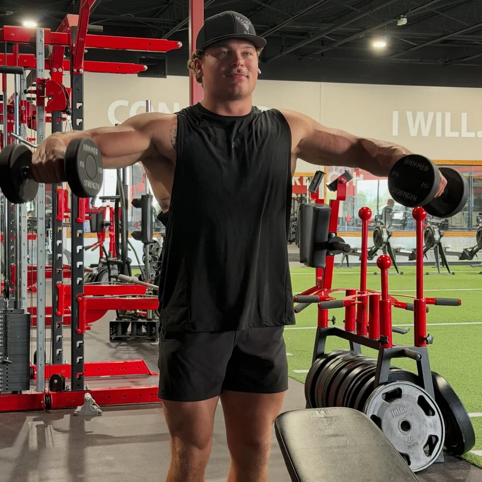 A T3 member performing a dumbbell lateral raise