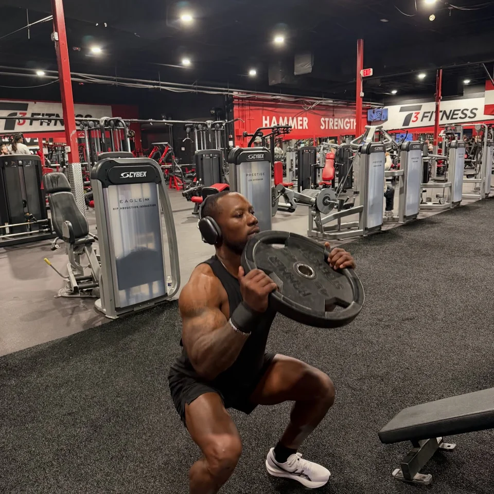 A T3 member squatting with a weight plate